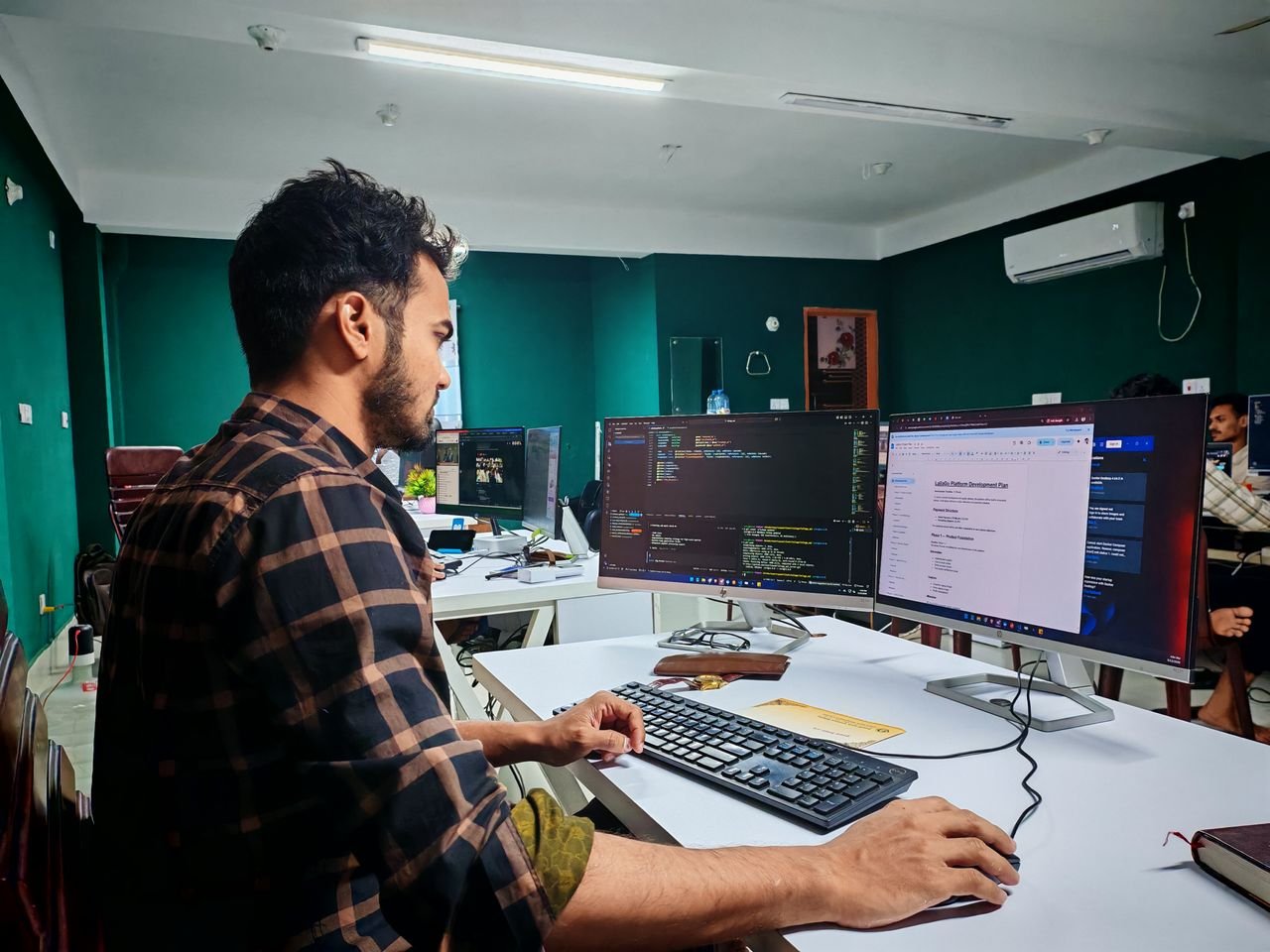 Developer working at dual monitors displaying code and documentation