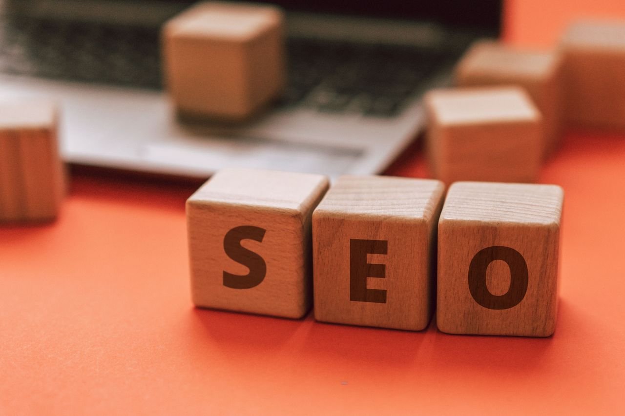 Wooden blocks spelling SEO next to a laptop