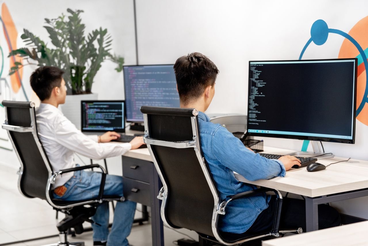 Two developers working together at dual monitors