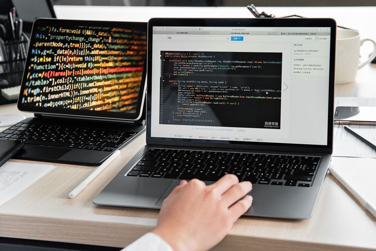 Laptop and tablet showing lines of code on a desk